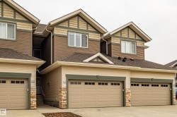 Contemporary multi-unit dwelling with integrated garages, two-tone siding, decorative stone accents, and peaked rooflines - 
