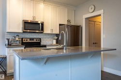 Kitchen featuring a central island with an integrated sink, polished chrome faucet, and extended countertop - 