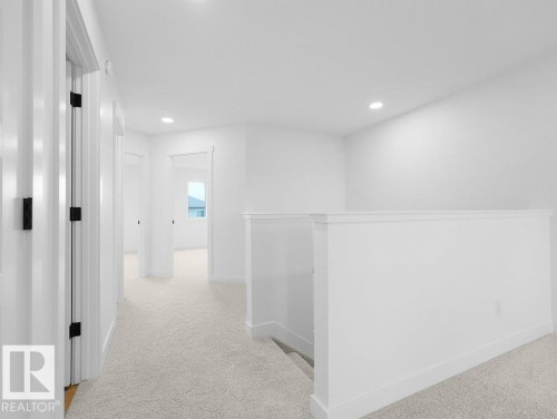 Upper-level landing with light carpeting, recessed lighting, white walls, and white trim - 912 17 Ave Nw, Edmonton, AB 