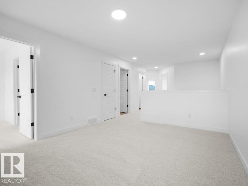 White painted walls, recessed lighting, white doors with matte black hardware, and light-colored carpeting - 912 17 Ave Nw, Edmonton, AB 