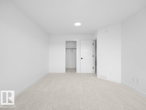 Recessed ceiling light, neutral carpeting, white interior walls, white paneled door, black door hardware - 912 17 Ave Nw, Edmonton, AB 
