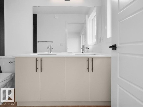 Dual vanity with integrated sinks, chrome hardware, light-toned cabinetry, and a large wall-mounted mirror - 912 17 Ave Nw, Edmonton, AB 