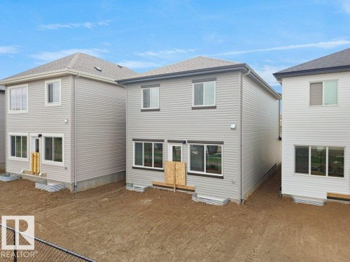 Rear exterior with light gray siding, multi-pane windows, and a dark shingle roof - 912 17 Ave Nw, Edmonton, AB 