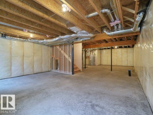 Unfinished lower level with exposed ceiling joists, insulated walls, and concrete flooring - 912 17 Ave Nw, Edmonton, AB 