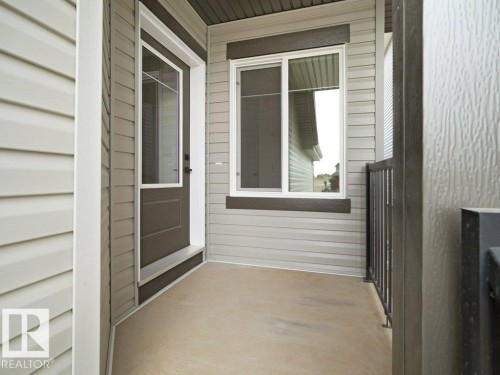 Front entry featuring a partial glass door, a bright window, textured siding, and a metal railing - 912 17 Ave Nw, Edmonton, AB 
