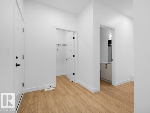 Wood-finish flooring, white paneled doors with black hardware, and a closet with wire shelving - 912 17 Ave Nw, Edmonton, AB 