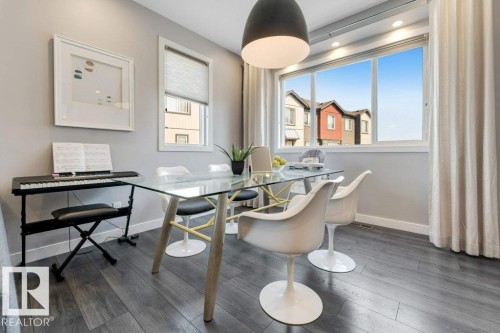 Dining area featuring wood-finish flooring, a large multi-pane window, recessed lighting, and a pendant light fixture - #45 16903 68 St Nw, Edmonton, AB 