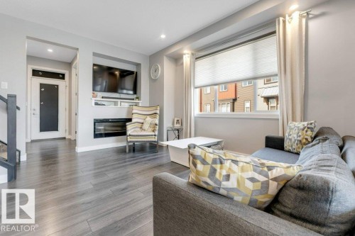 Living area featuring wood-finish flooring, recessed lighting, a built-in media center with shelving, and a large window with blinds - #45 16903 68 St Nw, Edmonton, AB 
