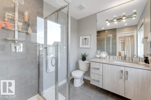 Glass-enclosed shower with a rainfall showerhead, full wall tiling, and a floating vanity with a single basin - #45 16903 68 St Nw, Edmonton, AB 