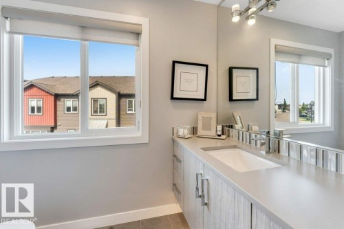 White framed window, light gray wall paint, built-in vanity with light wood-finish cabinetry, integrated sink, and polished chrome faucet - #45 16903 68 St Nw, Edmonton, AB 
