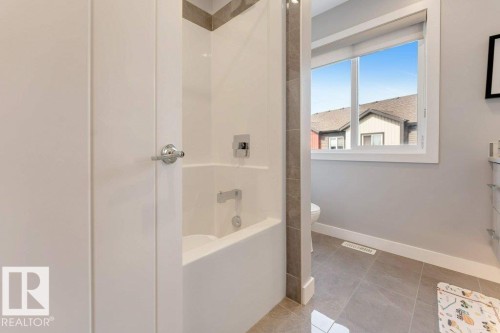 Built-in bathtub with shower, chrome fixtures, and tiled surround - #45 16903 68 St Nw, Edmonton, AB 