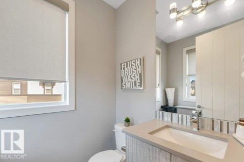 Vanity with integrated sink, stone countertop, wood-finish cabinetry, chrome faucet, and decorative tile backsplash - #45 16903 68 St Nw, Edmonton, AB 