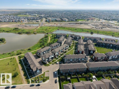 Aerial perspective showcasing a residential community with mature landscaping, multiple water features, and expansive green spaces - #45 16903 68 St Nw, Edmonton, AB 