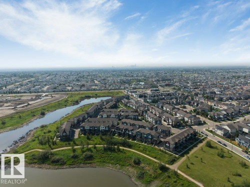Aerial perspective showcasing a residential development with a waterfront setting, bordered by a paved pathway and green spaces - #45 16903 68 St Nw, Edmonton, AB 