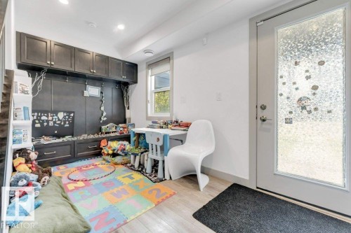 Built-in cabinetry with dark finishes, integrated shelving, wood-finish flooring, and a glass-paneled door - #45 16903 68 St Nw, Edmonton, AB 