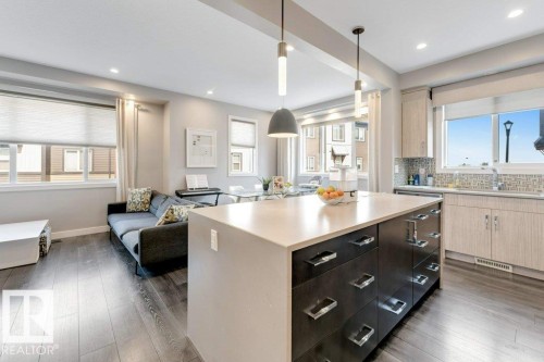 Open-concept living space featuring wood-finish flooring, recessed lighting, and a kitchen island with storage - #45 16903 68 St Nw, Edmonton, AB 