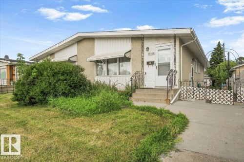 Stucco exterior with contrasting white siding accents, concrete steps with wrought iron railings, and an asphalt driveway - 13235 82 Street Nw, Edmonton, AB 