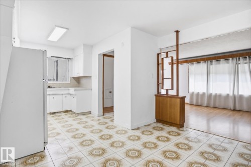 Kitchen with white cabinetry, patterned tile flooring, and a built-in room divider with wood-finish accents - 13235 82 Street Nw, Edmonton, AB 