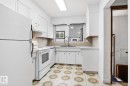 Kitchen featuring white cabinetry, a tile backsplash, a window above the sink, a built-in range, and patterned floor tiling - 13235 82 Street Nw, Edmonton, AB 