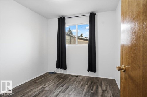 Window with natural light, wood-finish flooring, white walls, and a wood door with brass hardware - 13235 82 Street Nw, Edmonton, AB 