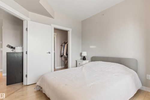 Light-toned wood-finish flooring complements neutral wall tones - #2205 10226 104 St Nw, Edmonton, AB - Indoor Photo Showing Bedroom