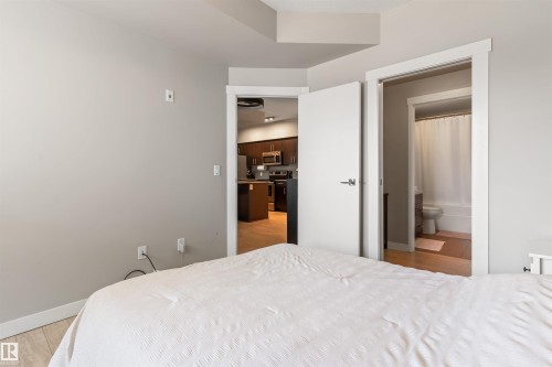 Bedroom featuring light wood-finish flooring, light grey painted walls, and white trim - #2205 10226 104 St Nw, Edmonton, AB - Indoor Photo Showing Bedroom