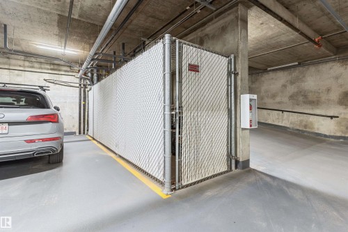 Dedicated parking space with a concrete floor, a white chain-link fence, and overhead piping - #2205 10226 104 St Nw, Edmonton, AB - Indoor Photo Showing Garage