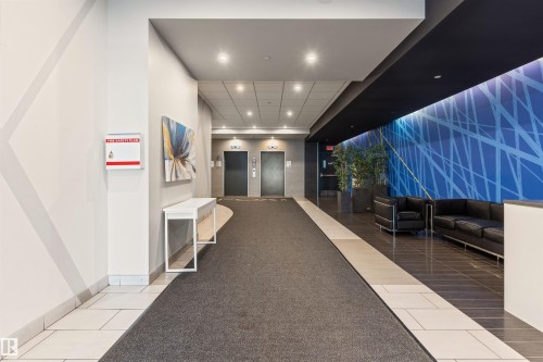 Contemporary lobby featuring recessed lighting, a blue accent wall with a geometric pattern, and dark tile flooring - #2205 10226 104 St Nw, Edmonton, AB - Indoor Photo Showing Other Room
