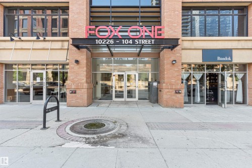 Modern building entrance featuring a brick facade and extensive glass storefronts - #2205 10226 104 St Nw, Edmonton, AB - Outdoor With Facade