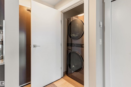Integrated stacked washer and dryer unit within a dedicated alcove - #2205 10226 104 St Nw, Edmonton, AB - Indoor Photo Showing Laundry Room