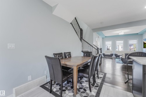 Open-concept living space featuring wood-finish flooring, a contemporary staircase with iron balusters, and recessed ceiling details - 6453 177A Avenue Nw, Edmonton, AB 