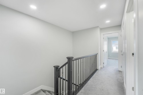 Recessed ceiling lighting, carpeted flooring, white trim, solid paneled doors, and a black wrought iron railing - 6453 177A Avenue Nw, Edmonton, AB 