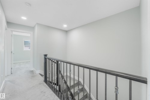 Carpeted hallway with recessed lighting and a wrought iron staircase railing - 6453 177A Avenue Nw, Edmonton, AB 