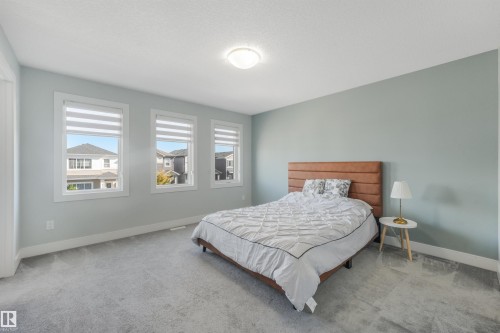 Light gray carpet flooring, three windows with horizontal blinds, light blue wall paint, and a flush mount ceiling light - 6453 177A Avenue Nw, Edmonton, AB 