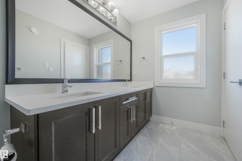 Double vanity with undermount sinks, white countertops, dark wood-finish cabinetry, and chrome fixtures - 6453 177A Avenue Nw, Edmonton, AB 