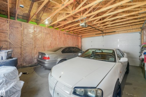 Attached garage with exposed wood rafters, concrete flooring, and an insulated wall - 6453 177A Avenue Nw, Edmonton, AB 