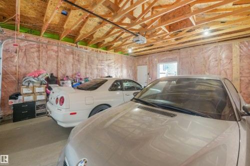 Spacious garage with exposed wood rafters, overhead lighting, and an automatic garage door opener - 6453 177A Avenue Nw, Edmonton, AB 