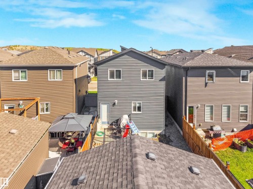Rear exterior featuring gray siding, multiple windows, and a back entry door - 6453 177A Avenue Nw, Edmonton, AB 