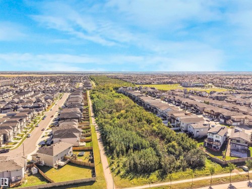 Residential neighborhood featuring detached and attached homes, tree-lined green space, and paved pathways - 6453 177A Avenue Nw, Edmonton, AB 