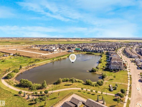 Scenic lakefront property featuring a pristine recreational pond with mature landscaping, manicured grounds, and tree-lined perimeter - 6453 177A Avenue Nw, Edmonton, AB 