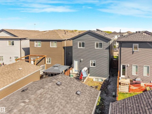 Rear exterior featuring dark gray siding, multiple windows, and a ground-level access door - 6453 177A Avenue Nw, Edmonton, AB 