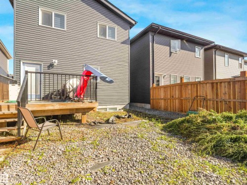 Rear exterior featuring gray horizontal siding, a wood deck with black metal railings, and a wooden privacy fence - 6453 177A Avenue Nw, Edmonton, AB 