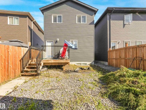 Rear exterior featuring gray horizontal siding, an elevated wood deck with black metal railings, and a gravel-covered yard - 6453 177A Avenue Nw, Edmonton, AB 