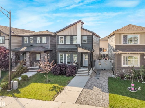 Modern two-story residence featuring a dark horizontal-stripe exterior with contrasting white trim, peaked roofline, and multi-pane windows - 6453 177A Avenue Nw, Edmonton, AB 