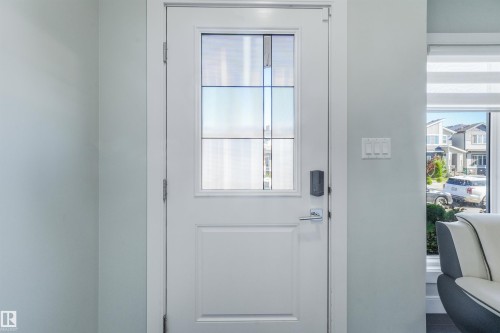 White paneled door with divided lite glass, chrome hardware, and smart lock - 6453 177A Avenue Nw, Edmonton, AB 