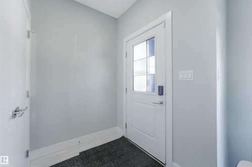 Entryway featuring a white paneled door with glass inserts, light grey walls, and light-toned tile flooring - 6453 177A Avenue Nw, Edmonton, AB 