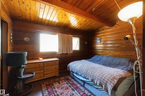 Interior room featuring extensive wood paneling on walls and ceiling, two windows, and wood-finish flooring - 910 Hermitage Avenue, Rural Parkland County, AB - Indoor Photo Showing Bedroom