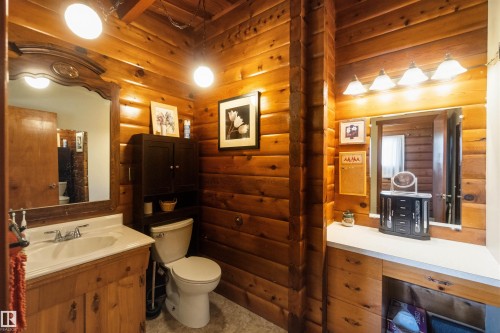 Wood-paneled bathroom featuring a vanity with an integrated sink, a separate counter space, and a toilet - 910 Hermitage Avenue, Rural Parkland County, AB - Indoor Photo Showing Bathroom