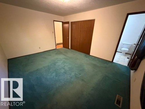Spacious room with teal carpeting, white walls, and built-in closet with wood-finish doors - 3 Morgan Crescent, St. Albert, AB 