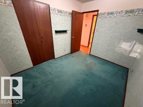 Wood-finish bi-fold closet doors, green patterned wallpaper, and green carpet flooring - 3 Morgan Crescent, St. Albert, AB 